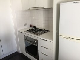 Una cocina compacta con estufa a gas, horno y refrigerador blanco.