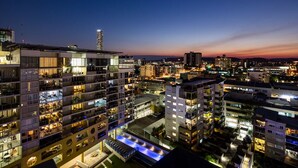 Un hotel de gran altura con varios pisos, balcones y una zona de piscina en la azotea.