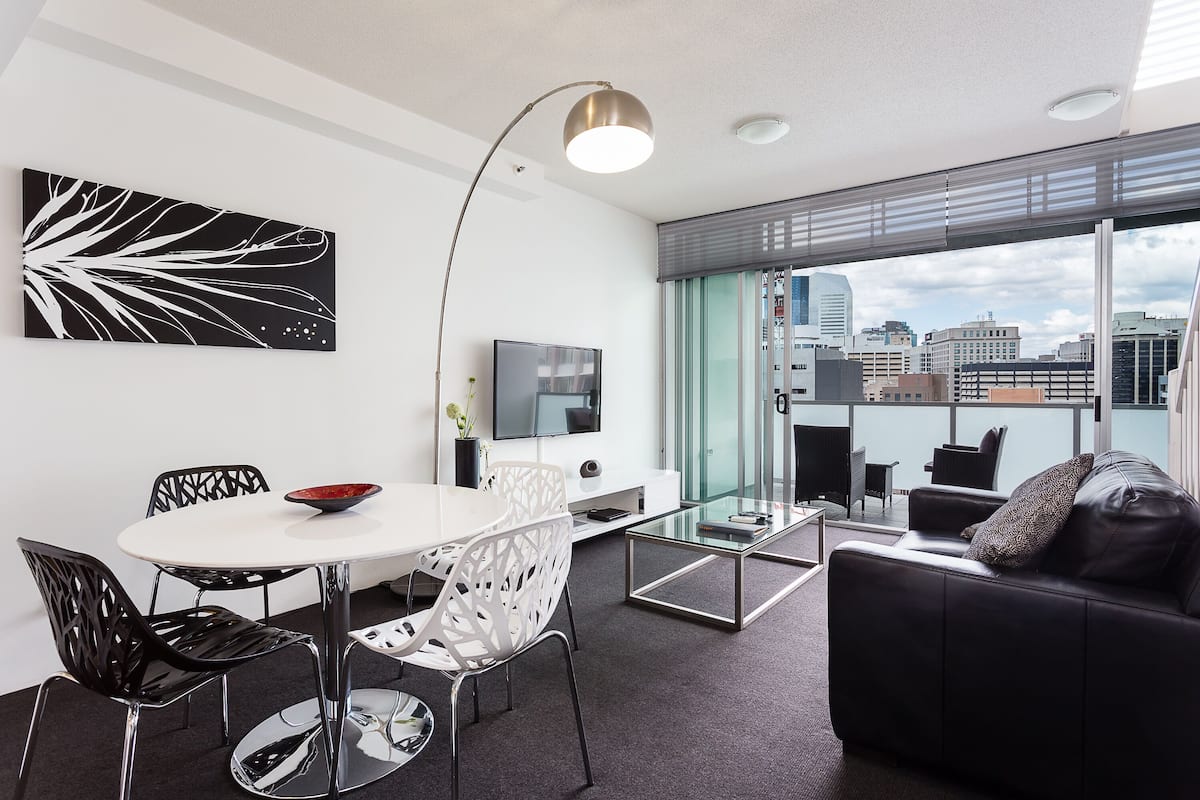 Una sala de estar moderna con comedor, un sofá y un televisor.