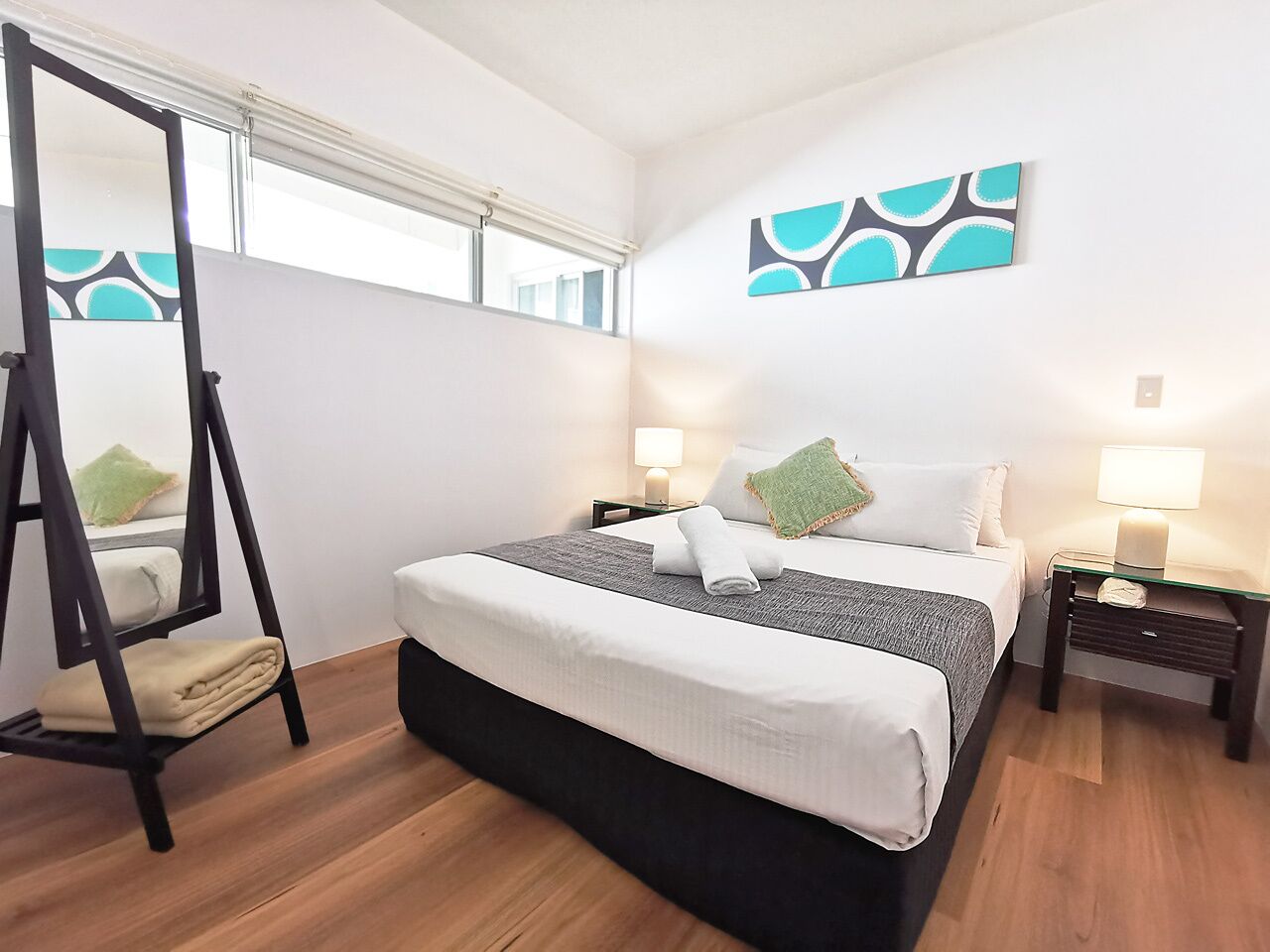 A bedroom with a bed, two bedside tables, a nightstand, a hanging chair, and a window with blinds.