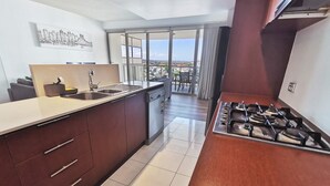 Una cocina moderna con una isla grande, una estufa a gas y vistas de la ciudad a través de amplios ventanales.