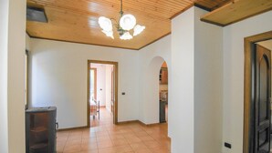 A spacious hallway with a wooden ceiling and tiled floor, leading to a kitchen area with cabinets and a countertop. - Beautiful home in Sesta Godano (Sesta Godano)