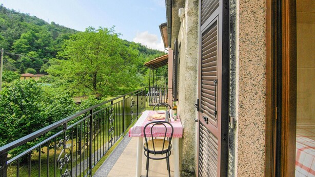 A balcony with a table and chairs, overlooking a lush green landscape and a mountain. - Beautiful home in Sesta Godano (Sesta Godano)
