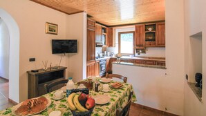 A dining area with a table set for a meal, a television mounted on the wall, wooden cabinets, and a window providing natural light. - Beautiful home in Sesta Godano (Sesta Godano)