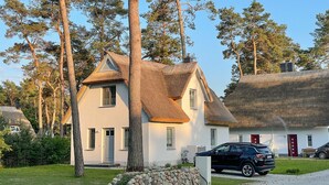 A house with a thatched roof and a stone wall in front.