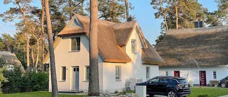 A house with a thatched roof and a stone wall in front.