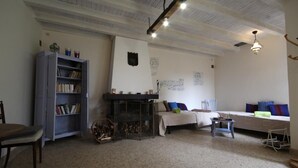 A cozy living room with a fireplace, a bookshelf, a sofa, and a dining area. - Le Tilleul - JALOGNY (JALOGNY)