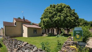 A stone wall, a house with a tiled roof, and a sign indicating 'Gite'. - Le Tilleul - JALOGNY (JALOGNY)