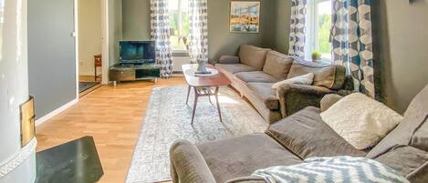 A living room with a sofa, a coffee table, a TV, and a rug.