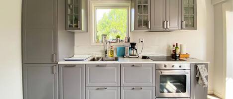 A modern kitchen with grey cabinets, a built-in oven, and a window providing natural light.