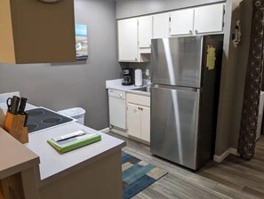 Compact kitchen with modern appliances, including a refrigerator, dishwasher, and stovetop, and a coffee maker.