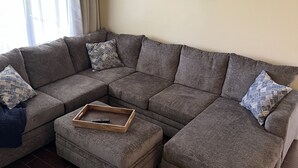 Una sala de estar con un sofá modular, una mesa de centro de madera y un adorno de pared.