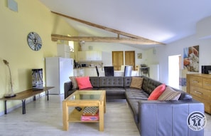 A living room with a sectional sofa, a coffee table, and a kitchen in the background.
