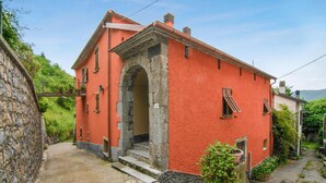 A red building with a stone archway entrance, a small porch, and a stone wall to the left. - 1 bedroom gorgeous apartment in Codivara (Codivara)