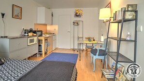 A compact room with a bed, kitchenette, desk, and a bookshelf. - Studio Berthelot 20 - Oullins (OULLINS)