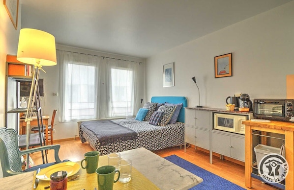 A compact bedroom with a bed, bedside table, and a desk with a chair.