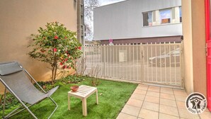 A small balcony with a chair, a table, and a potted plant. - Studio Berthelot 20 - Oullins (OULLINS)
