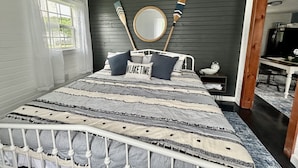 Un dormitorio con cama, un espejo y dos palas de madera en la pared.