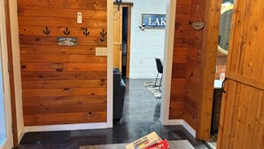 Interior de madera con ventilador de techo, un cartel que dice 'LAKE' y una cesta de juegos de mesa.