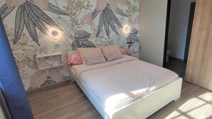 Ein Schlafzimmer mit einem Bett, einem Nachttisch und einer Wand mit Blätermotiv.