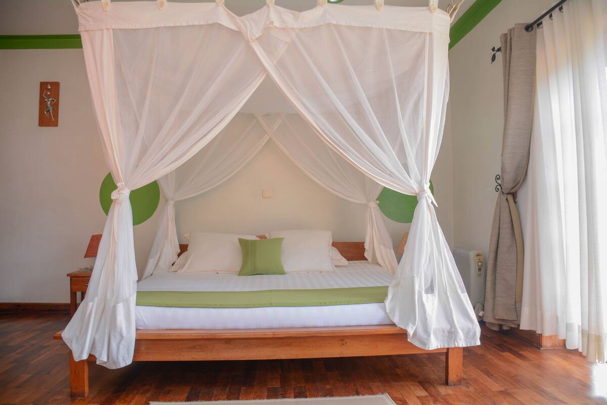 A bed with a canopy, a green pillow, and a white bedspread.