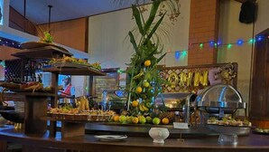 A bar area with a central island featuring a decorative plant arrangement and a glass of wine. - Andasibe Cyperus Hotel (Andasibe)