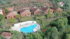 A residential area with multiple houses, a swimming pool, and lush greenery. - Andasibe Cyperus Hotel (Andasibe)