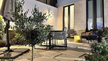 An outdoor patio area with a small tree, a bench, and a table.