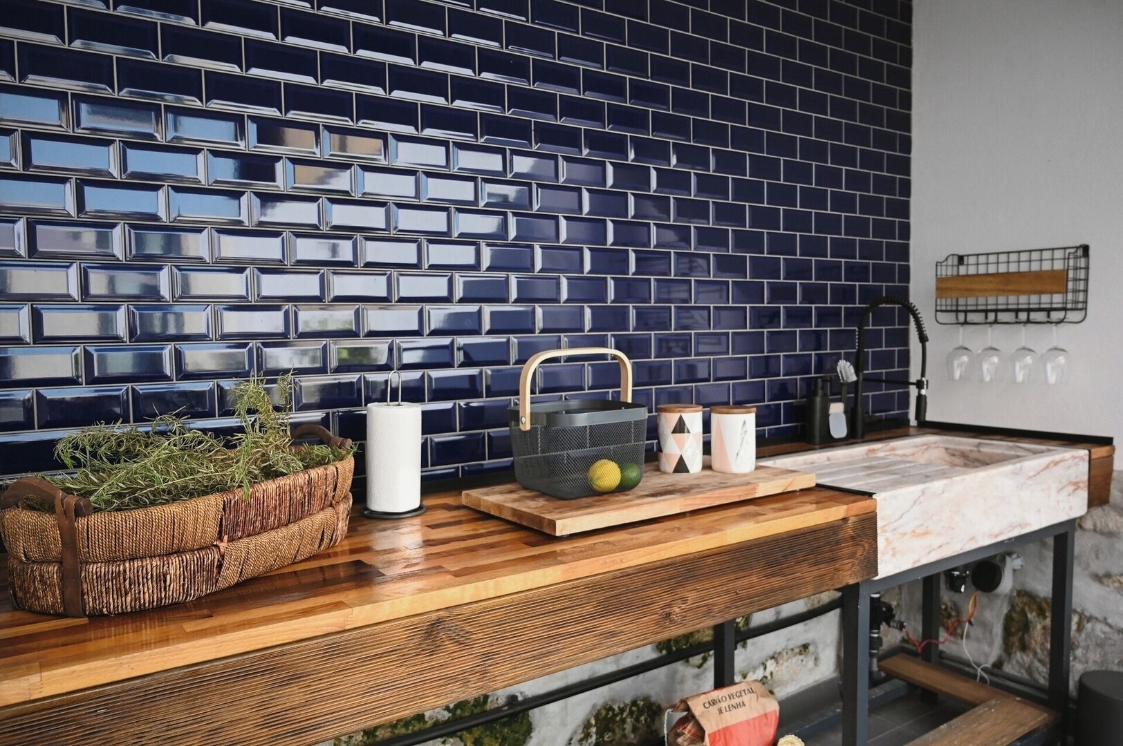 A kitchen with a blue-tiled backsplash, wooden countertop, and various kitchen items.