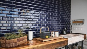 Una cocina con salpicadero de azulejos azules, encimera de madera y diversos utensilios.