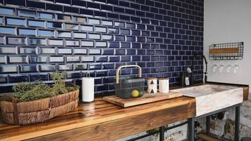 A kitchen with a blue-tiled backsplash, wooden countertop, and various kitchen items.