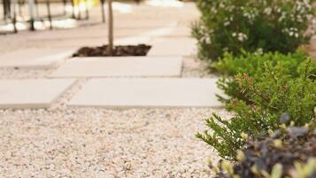 A pathway with pebbles leading to a seating area with tables and chairs.