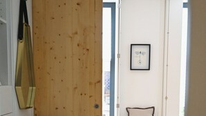 A bedroom with a wooden wall, a bed, a small stool, a chair, and a framed picture on the wall. - Douro Premium Garden | AC | BBQ (Vila Nova de Gaia)