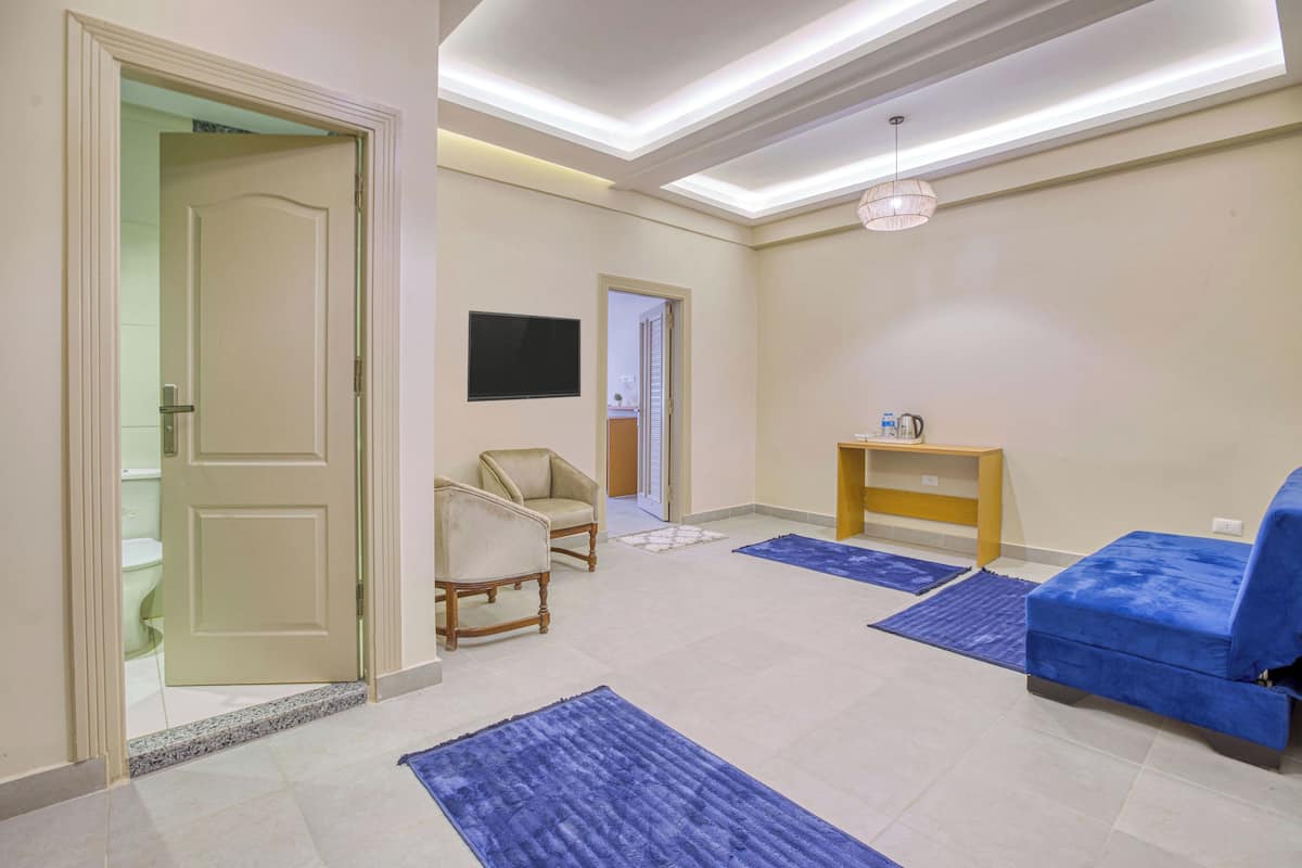 A hotel room with a bed, a chair, a small table, and a television.