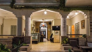 A lobby with a central staircase, a reception desk, and a seating area with chairs and tables. - Villa Khufu Pyramids Hotel (Giza)