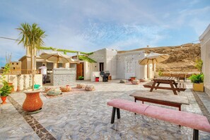 A courtyard with stone flooring, outdoor seating, and a palm tree.