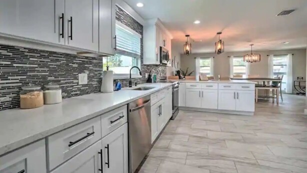 Una cocina amplia con armarios blancos, salpicadero de azulejos y una isla central.