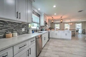 A spacious kitchen with white cabinets, a tiled backsplash, and a central island. - Cozy Safety Harbor Retreat w/ Heated Pool & Near Downtown (Safety Harbor)