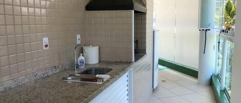 A kitchen with a sink, a stove, and a window overlooking a balcony.