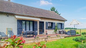 Une maison avec un patio, du mobilier d’extérieur et un jardin.