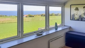 A room with three large windows overlooking a green field and the sea. - 3 bedroom cozy home in østermarie (Østermarie)