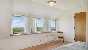 A bedroom with a large window, wooden floor, and a chair. - 3 bedroom cozy home in østermarie (Østermarie)