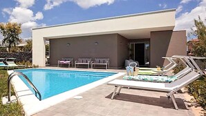 A modern pool area with a clear blue pool, lounge chairs, and a covered seating area. - Beautiful home in Mascalucia (Mascalucia)