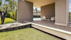 A modern outdoor patio area with a pool, white chairs, and a stone pathway. - Beautiful home in Mascalucia (Mascalucia)