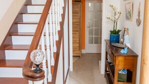A wooden staircase with white balusters, a wooden door with frosted glass panels, and a small wooden console table with a potted plant and decorative items.