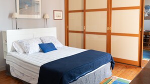 A bedroom with a bed, a wardrobe, and a painting on the wall.