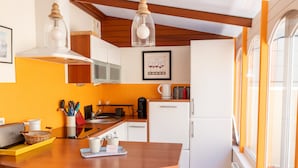 A kitchen with a wooden island, white appliances, and a window with orange frames.