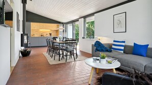Een moderne woonruimte met een eethoek, een bank met blauwe kussens, en een keuken op de achtergrond.