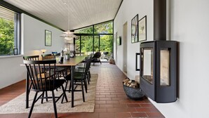 Een moderne eethoek met een lange tafel, stoelen en een open haard.