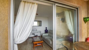 Una habitación con puerta corrediza de vidrio, un sofá, una pequeña mesa y una silla.